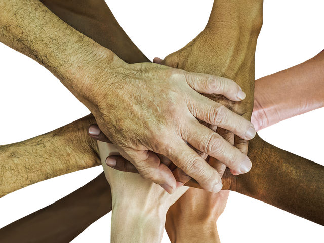 A group of diverse hands stacked on top of one another symbolizing teamwork.
